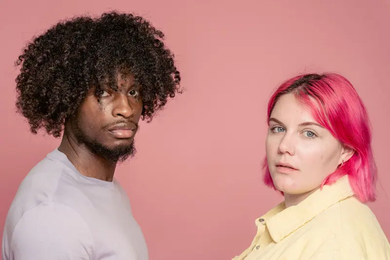 Couple against pink, one with big curls