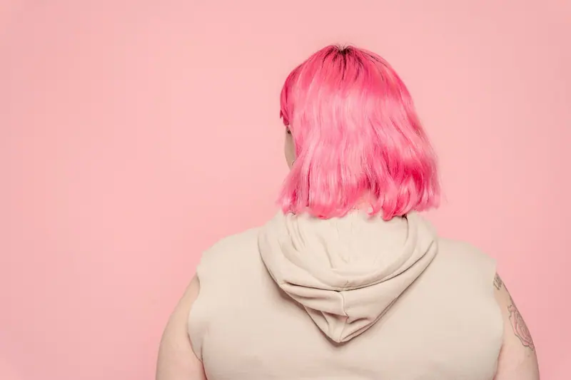 Pink hair and a white hoodie in a minimal studio