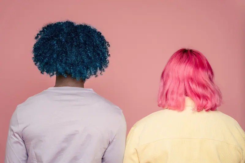 Two clients from behind, one with a navy afro and one with a pink bob