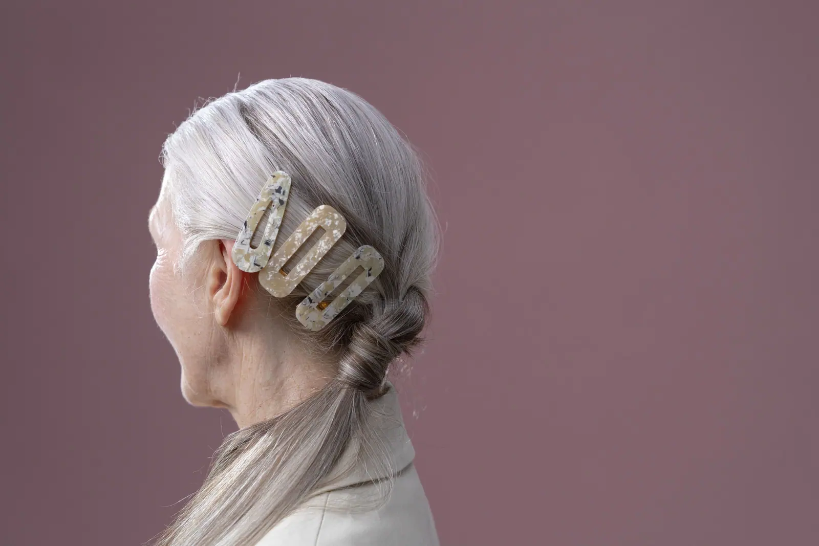 Close-up portrait of a senior woman with a stylish hair barrette in a studio setting.